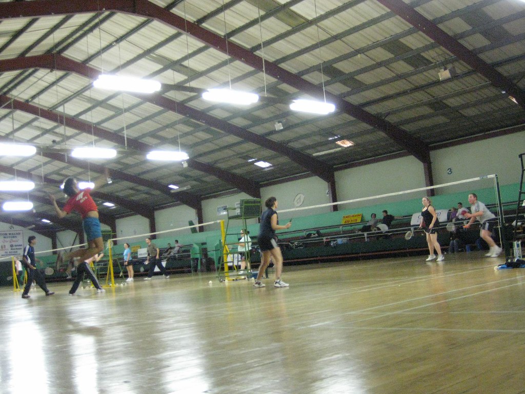 Club badminton rally across multiple courts